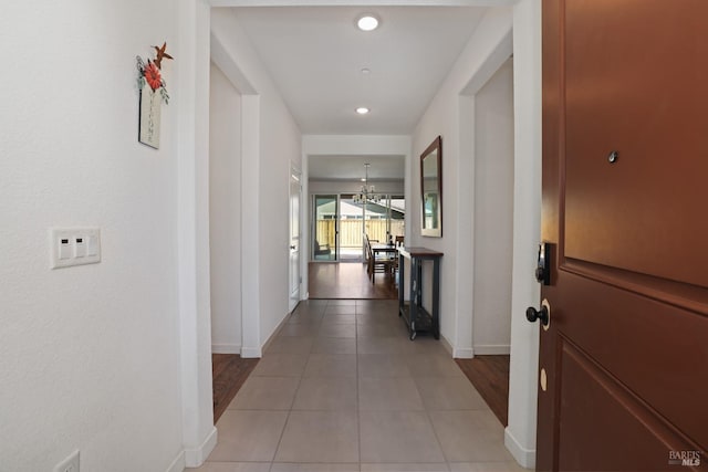 hall with a notable chandelier, light tile patterned flooring, recessed lighting, and baseboards