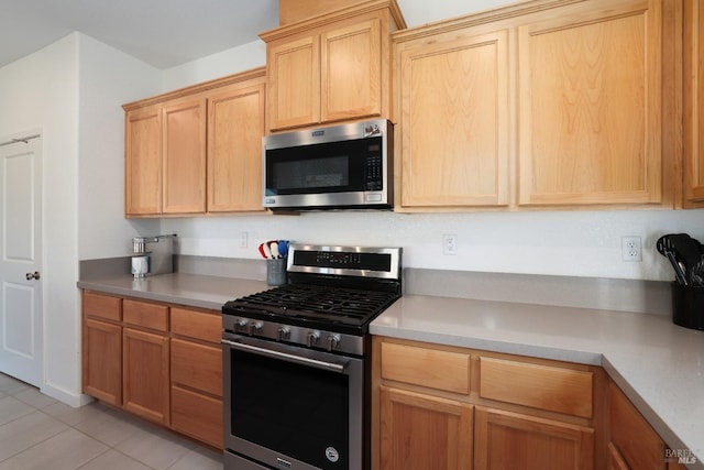 kitchen with light tile patterned floors, stainless steel appliances, light countertops, and light brown cabinetry