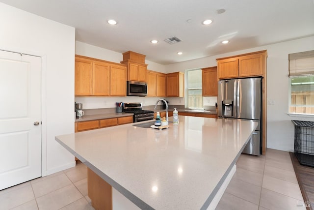 kitchen with visible vents, a kitchen island with sink, a sink, appliances with stainless steel finishes, and light countertops