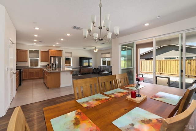 dining space with light tile patterned floors, visible vents, recessed lighting, and ceiling fan with notable chandelier