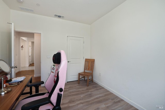 office space with light wood finished floors, visible vents, and baseboards