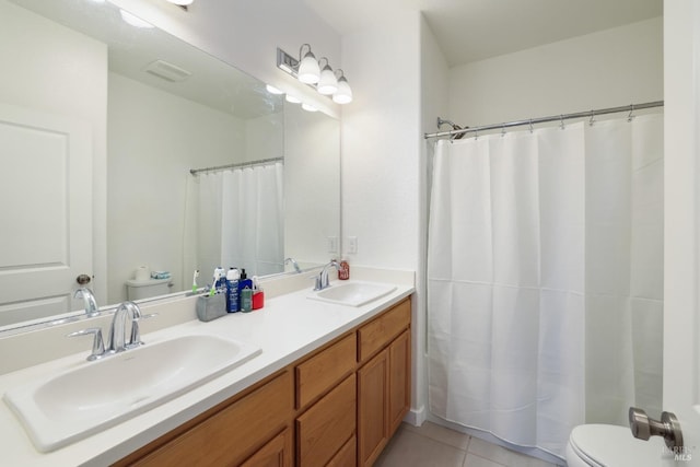 bathroom with a sink, toilet, double vanity, and tile patterned floors