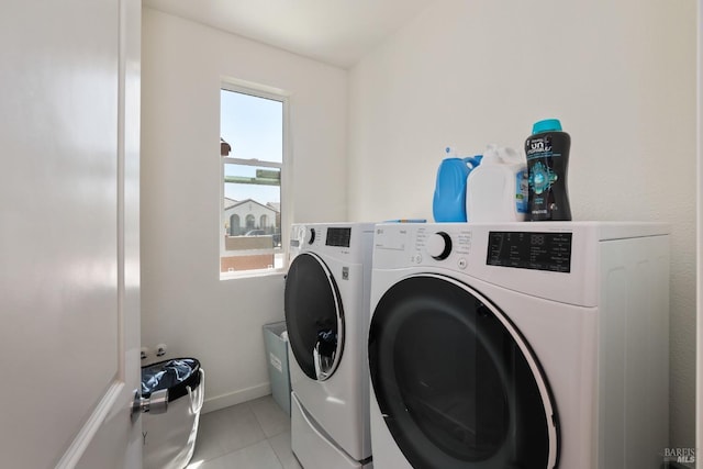 laundry room featuring washing machine and clothes dryer, laundry area, baseboards, and light tile patterned floors