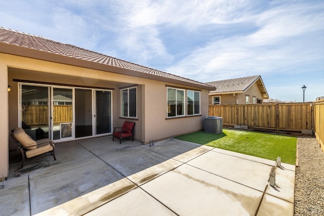 rear view of house with stucco siding, a tile roof, a fenced backyard, a yard, and a patio area