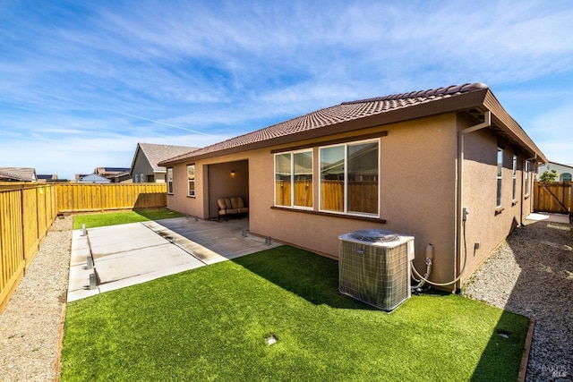 rear view of property featuring central air condition unit, stucco siding, a lawn, a fenced backyard, and a patio area