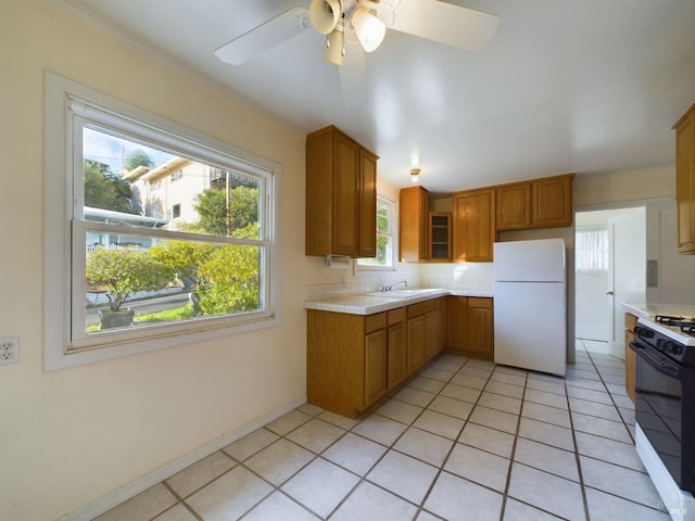 kitchen with range with gas stovetop, tile countertops, light tile patterned floors, freestanding refrigerator, and ceiling fan