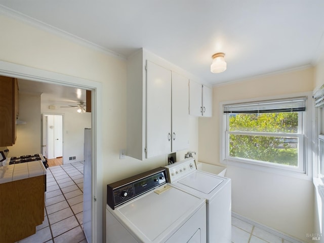 laundry area with light tile patterned floors, cabinet space, crown molding, and washer and clothes dryer