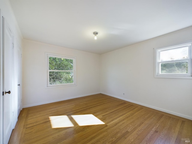 unfurnished room with light wood-style flooring and baseboards