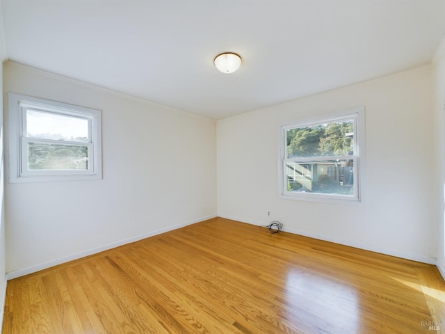 spare room with baseboards and light wood-style floors