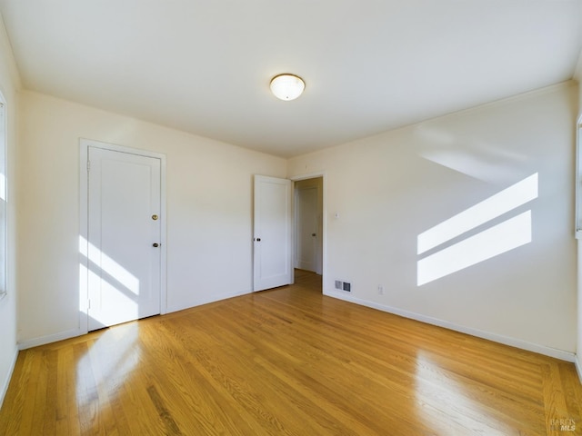 unfurnished room with baseboards, visible vents, and light wood-type flooring