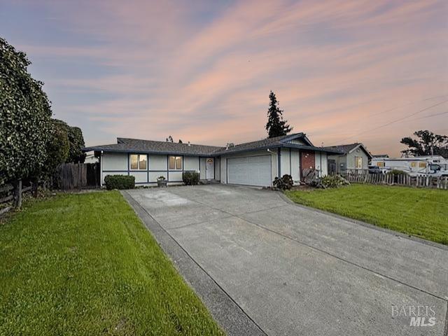 single story home featuring a garage, a yard, driveway, and fence