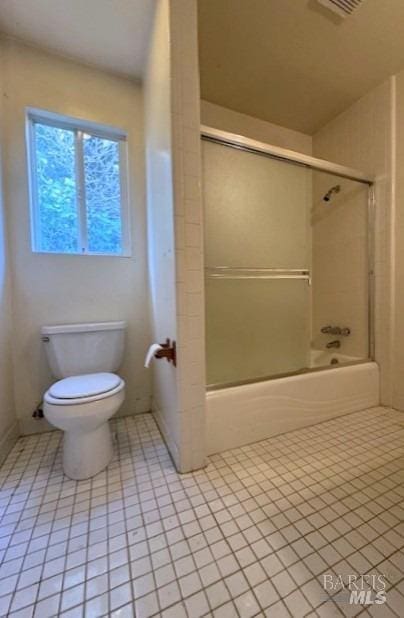 full bath with tile patterned flooring, combined bath / shower with glass door, visible vents, and toilet