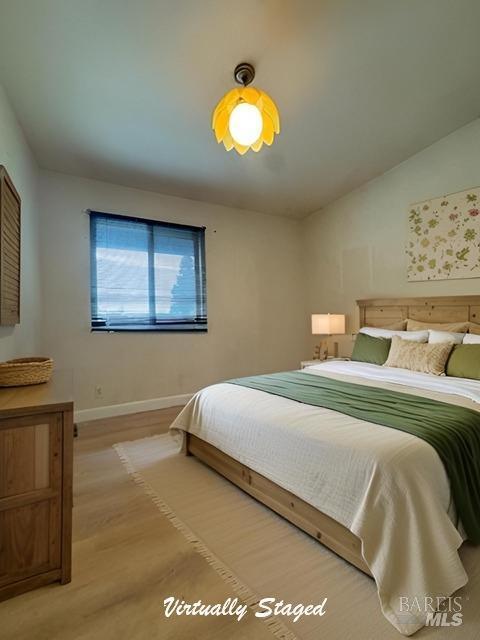 bedroom featuring light wood-type flooring, baseboards, and vaulted ceiling