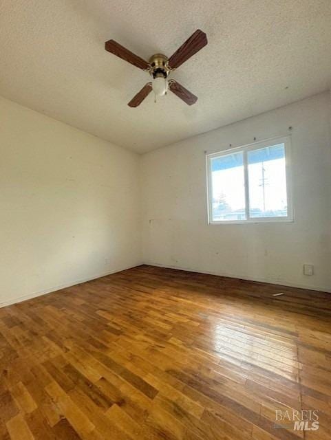 unfurnished room featuring hardwood / wood-style flooring, a ceiling fan, and a textured ceiling