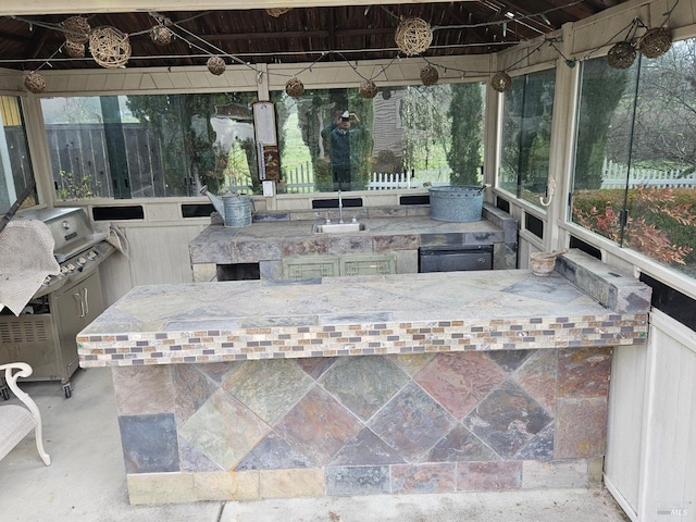 view of patio / terrace with an outdoor kitchen, fence, a sink, and outdoor wet bar