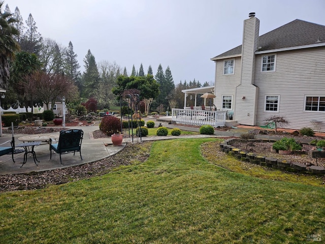 view of yard with a wooden deck and a patio
