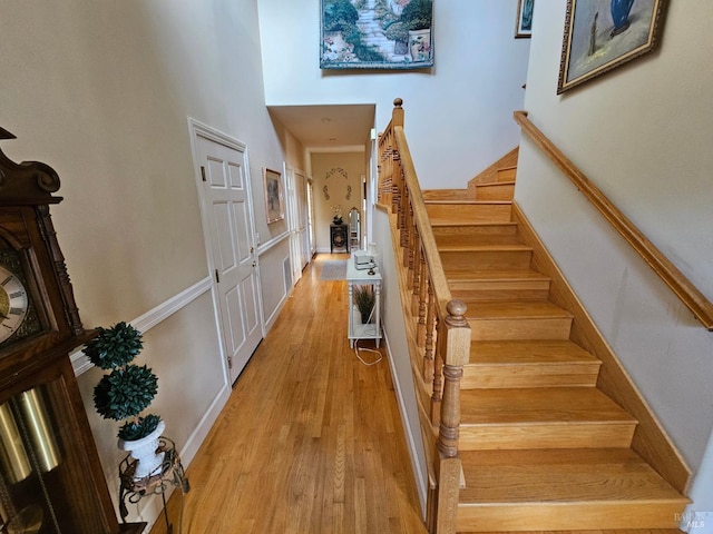 stairway with a high ceiling and wood finished floors