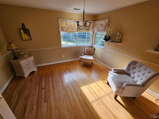 living area with visible vents, baseboards, ornamental molding, wood finished floors, and an inviting chandelier