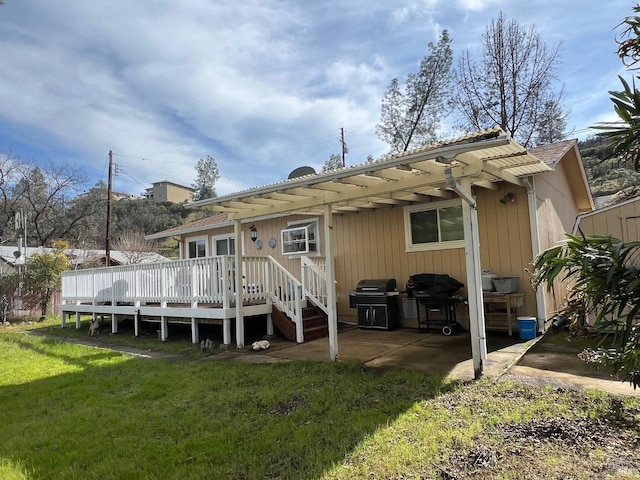 rear view of property featuring a wooden deck, a lawn, and a patio area