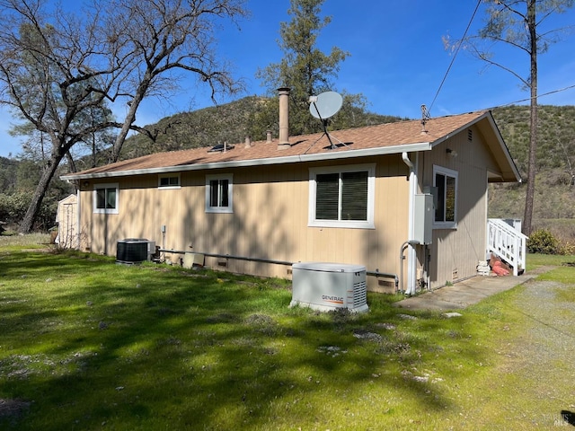 rear view of house with a shingled roof, a lawn, and crawl space