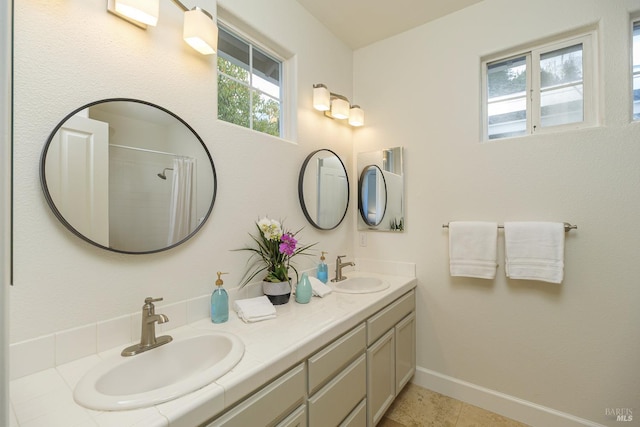 bathroom with tile patterned flooring, double vanity, baseboards, and a sink