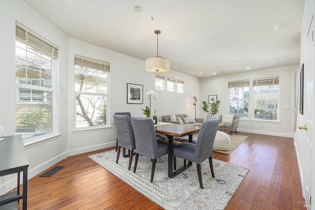 dining space with visible vents, a healthy amount of sunlight, baseboards, and hardwood / wood-style flooring