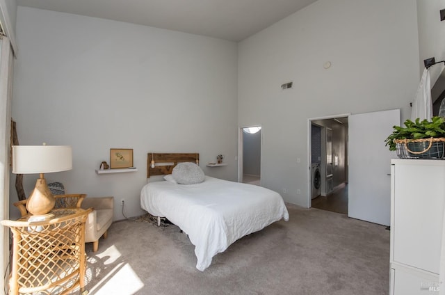 carpeted bedroom featuring washer / dryer, a high ceiling, and visible vents