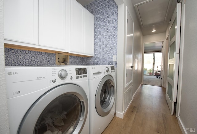 laundry room featuring cabinet space, light wood-style floors, baseboards, attic access, and washing machine and clothes dryer