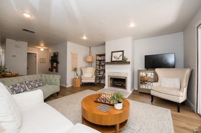 living area with visible vents, recessed lighting, a fireplace, and light wood-type flooring