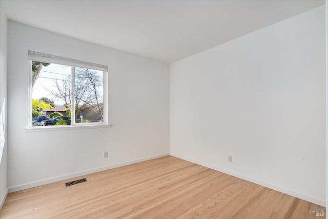 spare room with visible vents, baseboards, and wood finished floors