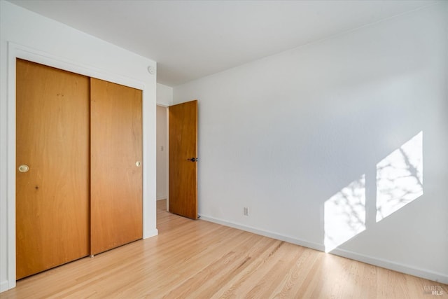 unfurnished bedroom with a closet, wood finished floors, and baseboards