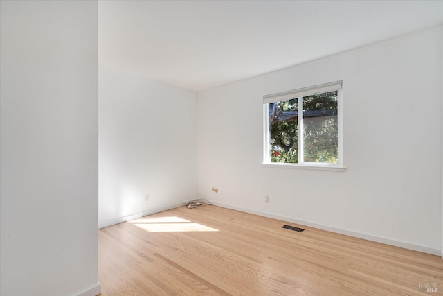 empty room featuring baseboards, visible vents, and wood finished floors