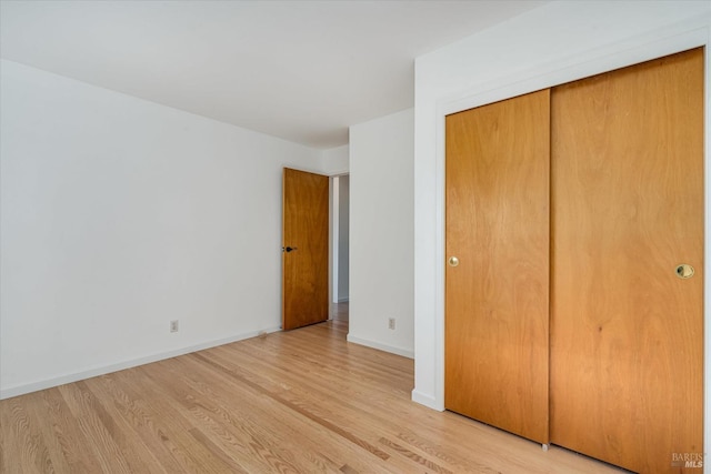 unfurnished bedroom with a closet, baseboards, and light wood finished floors