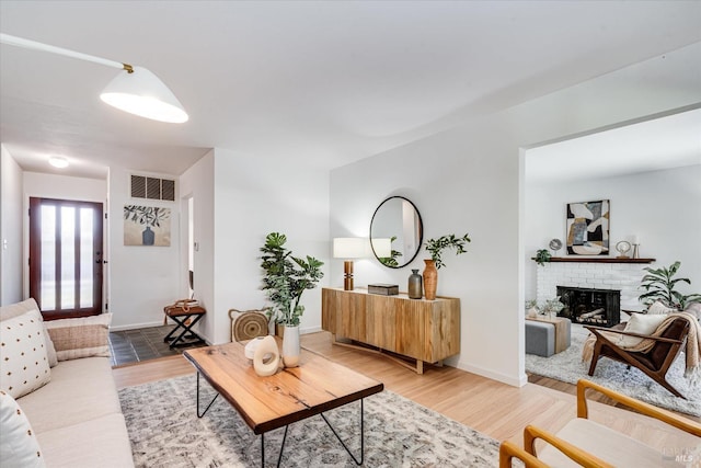 living area with visible vents, a fireplace, light wood-style flooring, and baseboards