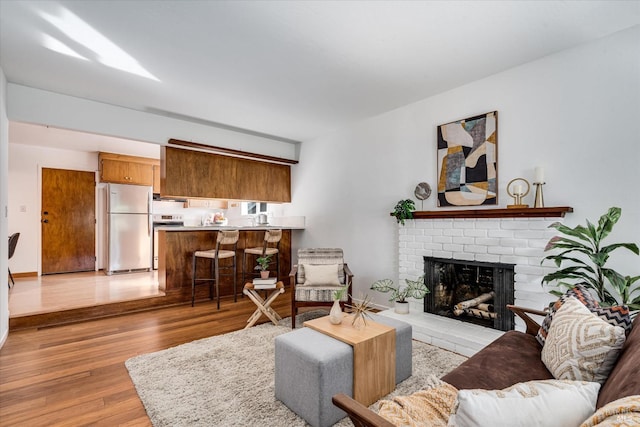 living room featuring light wood-type flooring and a brick fireplace