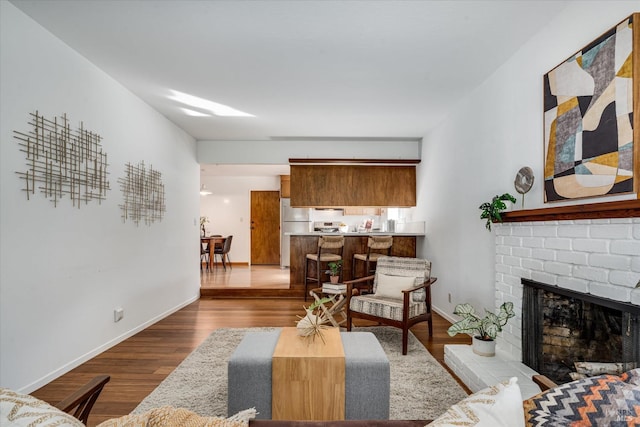 living room featuring a fireplace, wood finished floors, and baseboards