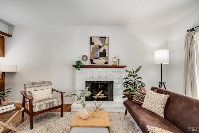 living room with a brick fireplace, wood finished floors, and baseboards