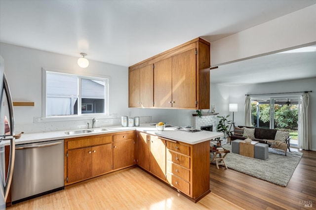 kitchen featuring a fireplace, light countertops, appliances with stainless steel finishes, open floor plan, and a sink