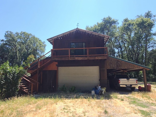 exterior space with a garage, dirt driveway, stairway, a wooden deck, and a carport