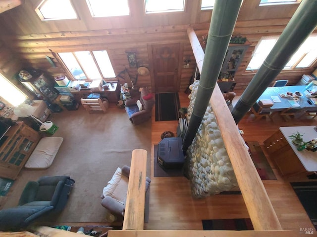 living room featuring a wood stove, a high ceiling, log walls, and wood finished floors