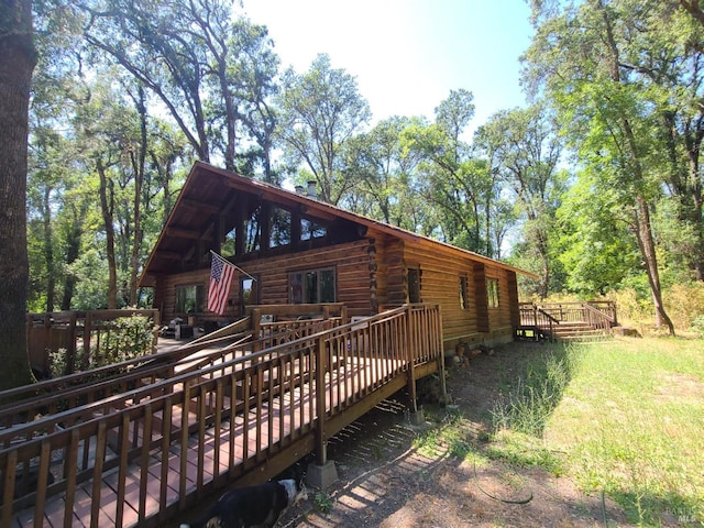 view of side of home with log siding and a wooden deck