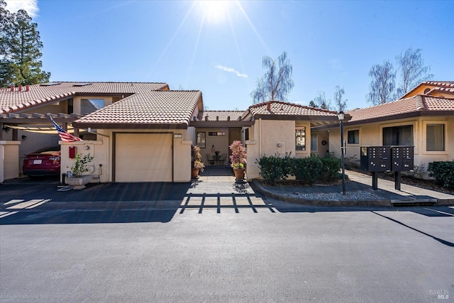 view of front of property featuring a tiled roof, an attached garage, and stucco siding