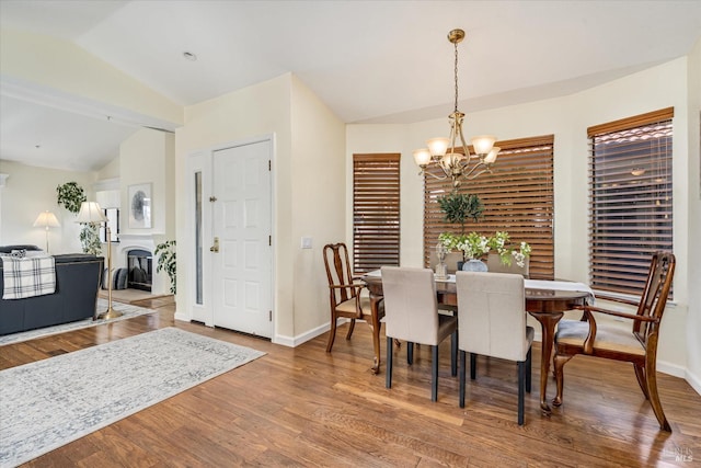 dining area featuring lofted ceiling, baseboards, wood finished floors, and a notable chandelier