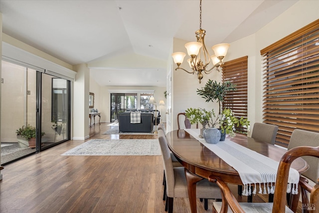 dining room featuring vaulted ceiling, baseboards, wood finished floors, and a chandelier