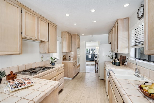 kitchen with white appliances, tile countertops, and light brown cabinetry