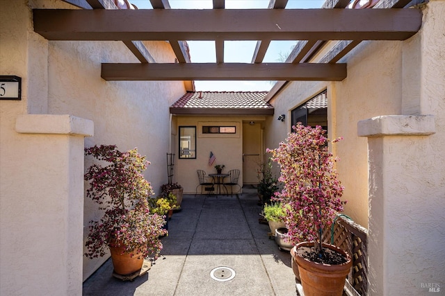 doorway to property with a patio area, a tile roof, and stucco siding