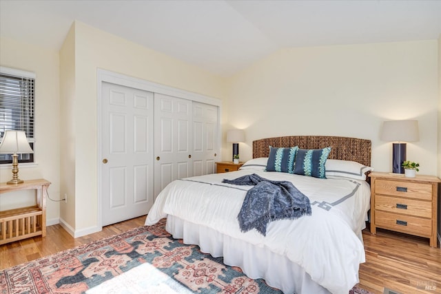 bedroom featuring lofted ceiling, a closet, baseboards, and wood finished floors