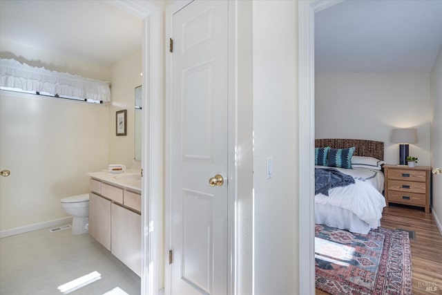 bathroom featuring baseboards, visible vents, toilet, wood finished floors, and vanity