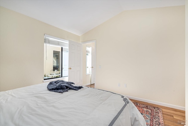 bedroom featuring lofted ceiling, baseboards, and light wood-style floors