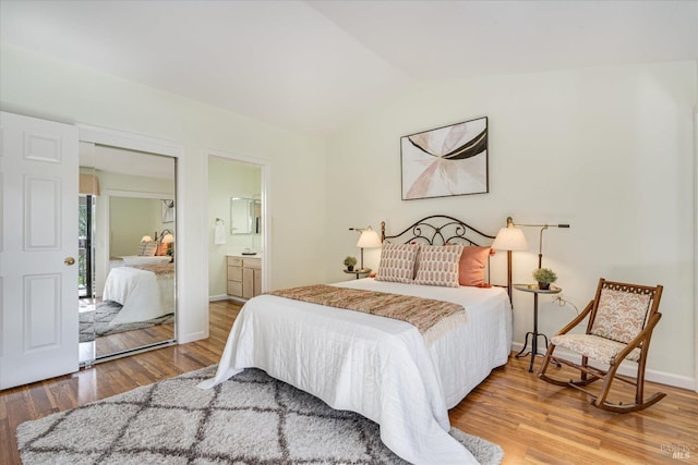 bedroom with vaulted ceiling, baseboards, and wood finished floors